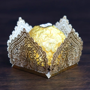 Macro view of laser-cut gold lace candy wrapper with intricate floral pattern
