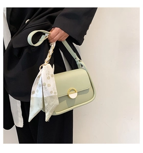 Détail du sac selle vert menthe avec ruban de soie cerise et boucle ronde dorée chic