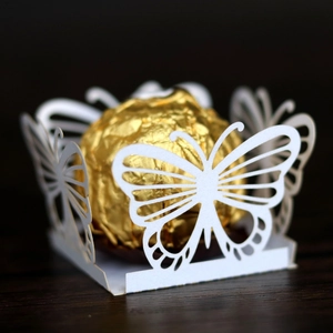 Macro view of white butterfly-shaped laser-cut candy holder with golden chocolate