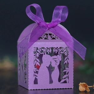 Macro shot of purple laser-cut wedding candy box with couple silhouette and ribbon
