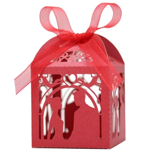 Detail of red laser-cut wedding favor box with romantic silhouettes and organza bow