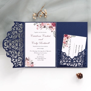 Macro view of laser-cut floral pattern and navy pearl paper wedding invite kit