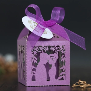 Détail de boîte à bonbons de mariage ajourée violette avec ruban et étiquette de merci