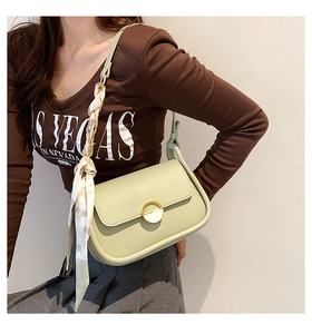 Détail d'un sac selle vert menthe avec boucle dorée et foulard en soie décoratif