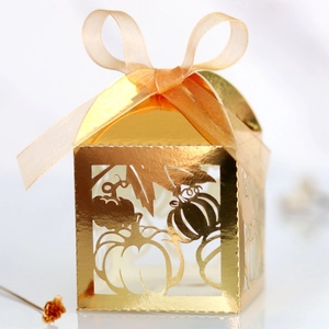 Detailed close-up of golden laser-cut pumpkin candy box with elegant silk ribbon bow