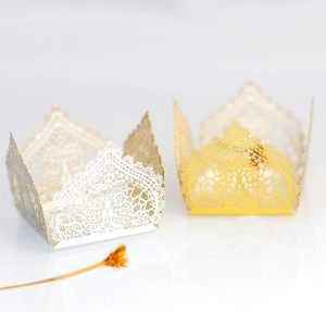 Macro detail of laser-cut gold and white lace candy boxes for wedding party decor