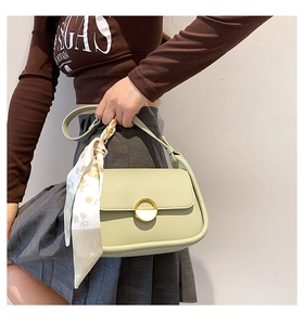 Détail du sac selle vert clair avec boucle dorée et décor de foulard en soie fleurie
