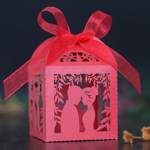 Detail of red laser-cut wedding favor box with romantic couple silhouette and ribbon bow