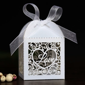 Detail showing white laser-cut LOVE candy box with ornate hollow patterns and organza ribbon