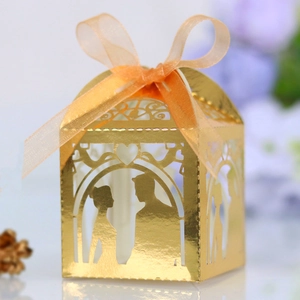 Macro detail of gold laser-cut wedding favor box with bride groom heart silhouette