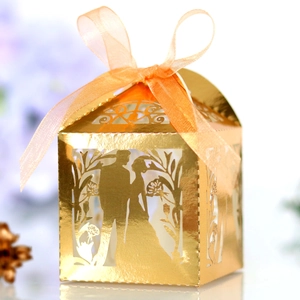 Detail of laser-cut hollow wedding favor box with gold finish and organza ribbon