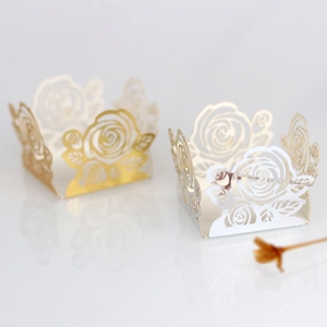 Détail de motifs de roses découpés au laser sur des caissettes à cupcakes or et blanches