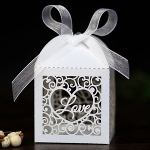 Macro view of white laser-cut LOVE candy box with pearlescent paper and organza ribbon