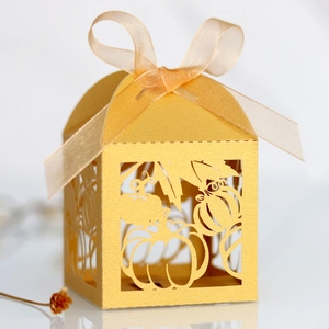 Macro shot of laser-cut gold pumpkin and maple leaf patterns on a pearlescent gift box