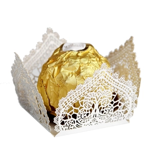 Close-up of white laser-cut hollow lace candy box with a golden chocolate inside