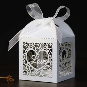 Close-up of laser-cut Love heart patterns and white ribbon on wedding candy box