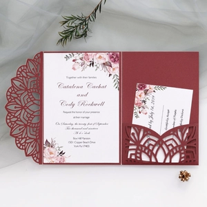 Close-up of burgundy laser-cut wedding invitation set with floral patterns and RSVP cards