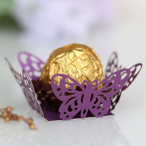 Detail of purple laser-cut butterfly candy box holding a gold-wrapped chocolate truffle