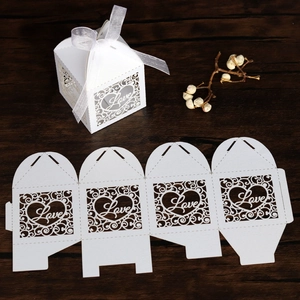 Detail of white laser-cut wedding favor box with Love heart pattern and silk ribbon