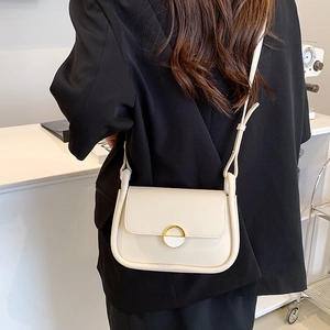 Mini sac selle crème chic avec boucle dorée porté sur une tenue de blazer noir