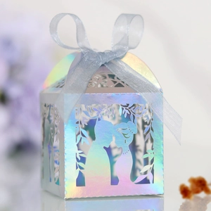 Macro shot of laser-cut iridescent wedding candy box with couple silhouette and blue ribbon