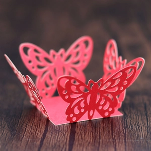 Close-up of laser-cut red butterfly cupcake wrappers with intricate hollow patterns