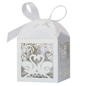 Detail of laser-cut white wedding favor box with swan heart design and satin ribbon