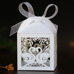 Macro detail of laser-cut white swan heart candy box with elegant organza ribbon bow