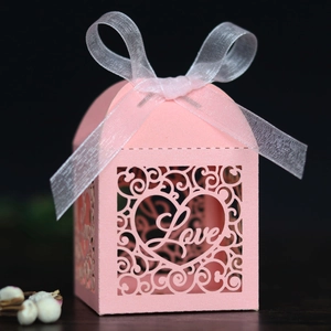 Detail of pink laser-cut wedding favor box with Love heart motif and organza ribbon bow