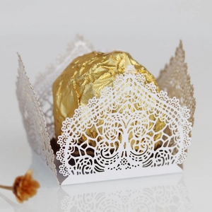 Close-up of laser cut white paper candy wrapper with intricate lace patterns and chocolate