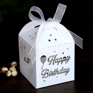 Close-up of laser-cut Happy Birthday favor box in white paper with organza ribbon