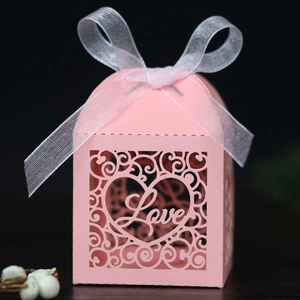 Detail of pink laser-cut wedding favor box with Love script and white ribbon bow