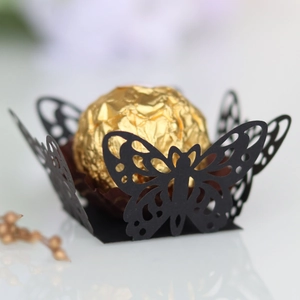 Macro shot of laser-cut black butterfly paper candy holder with golden foil chocolate