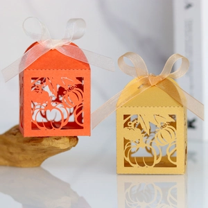 Detail of laser-cut pumpkin favor boxes with orange and gold ribbons for Thanksgiving
