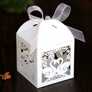 Macro shot of white laser cut swan wedding candy favor box with ribbon detail
