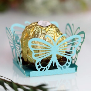 Detailed laser-cut butterfly wedding candy box in pearlescent blue with a chocolate inside