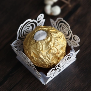 Détail de l'emballage en papier blanc découpé au laser avec motif rose pour bonbons de mariage