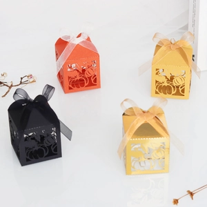 Detail of laser-cut pumpkin favor boxes with decorative ribbons in gold and orange
