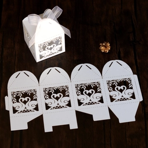 Detailed laser-cut white swan candy boxes with heart pattern and white silk ribbons