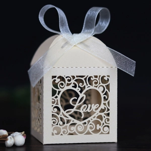 Macro detail of laser-cut heart pattern and LOVE text on cream wedding favor box