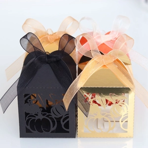Detail of laser-cut pumpkin favor boxes with ribbons in gold, black and orange