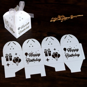 Flat lay showing unassembled laser-cut paper candy box with Happy Birthday ribbon