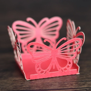 Close-up of pink laser-cut butterfly candy box with intricate lace details on wood