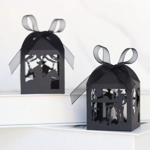 Detail of black laser-cut candy boxes with cowboy horse silhouettes and organza ribbons