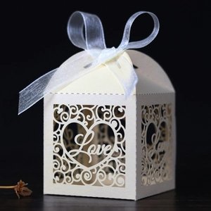 Macro detail of laser-cut heart pattern and LOVE text on pearlescent wedding candy box