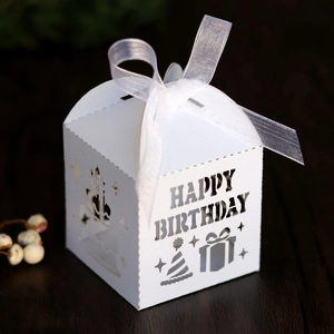 Detailed laser-cut Happy Birthday candy box with white ribbon on a wooden background