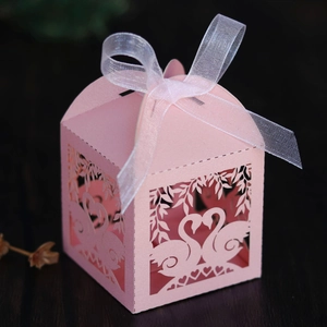 Detail view of pink laser-cut swan gift box with ribbon for wedding party favors