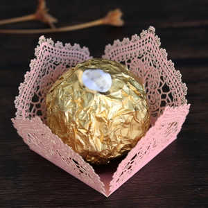 Macro view of pink laser-cut lace chocolate wrapper with elegant hollowed floral patterns