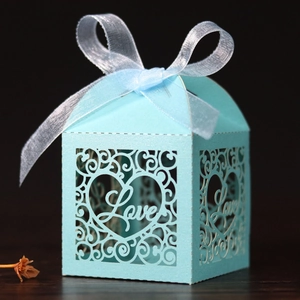 Macro shot of laser-cut pearl paper candy box with Love heart pattern and blue ribbon