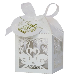 Detail of white laser-cut wedding favor box with swan heart design and ribbon tag